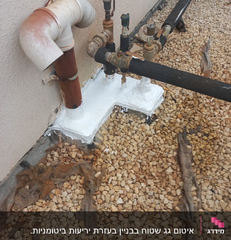צינורות ואביזרים אטומים בחומר לבן על קרקע חצץ